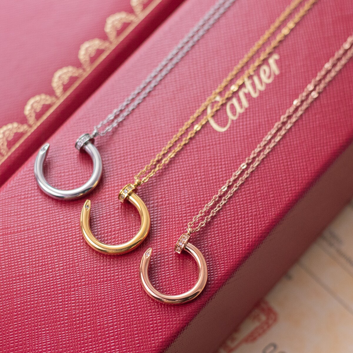 Nail motif pendant necklaces in three finishes laid out together
