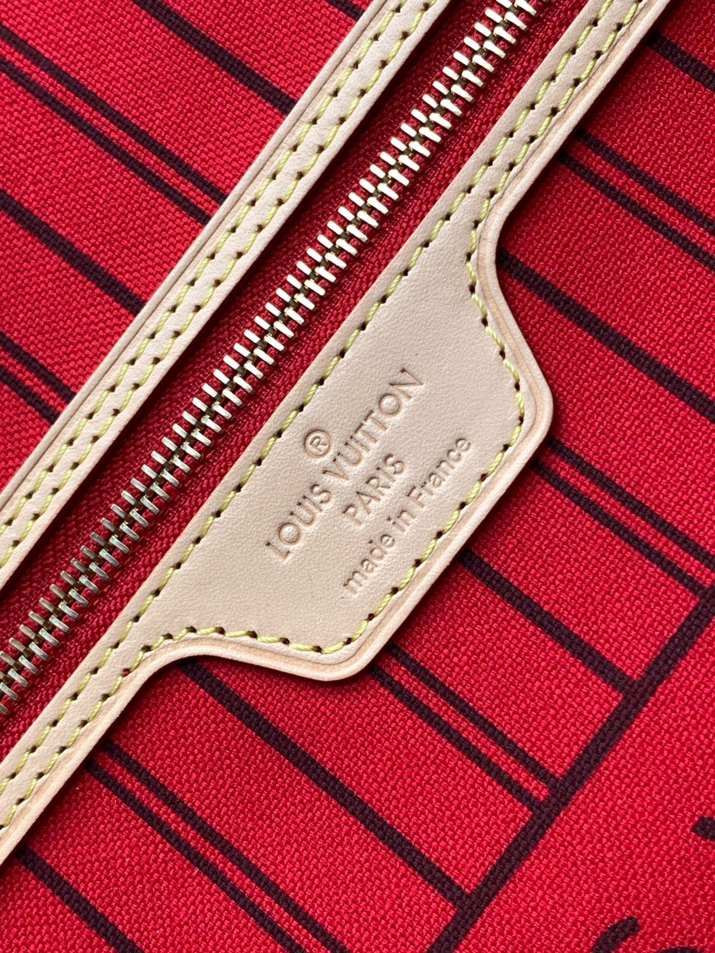 Close view of the interior stamped leather tab and zipper against the striped lining