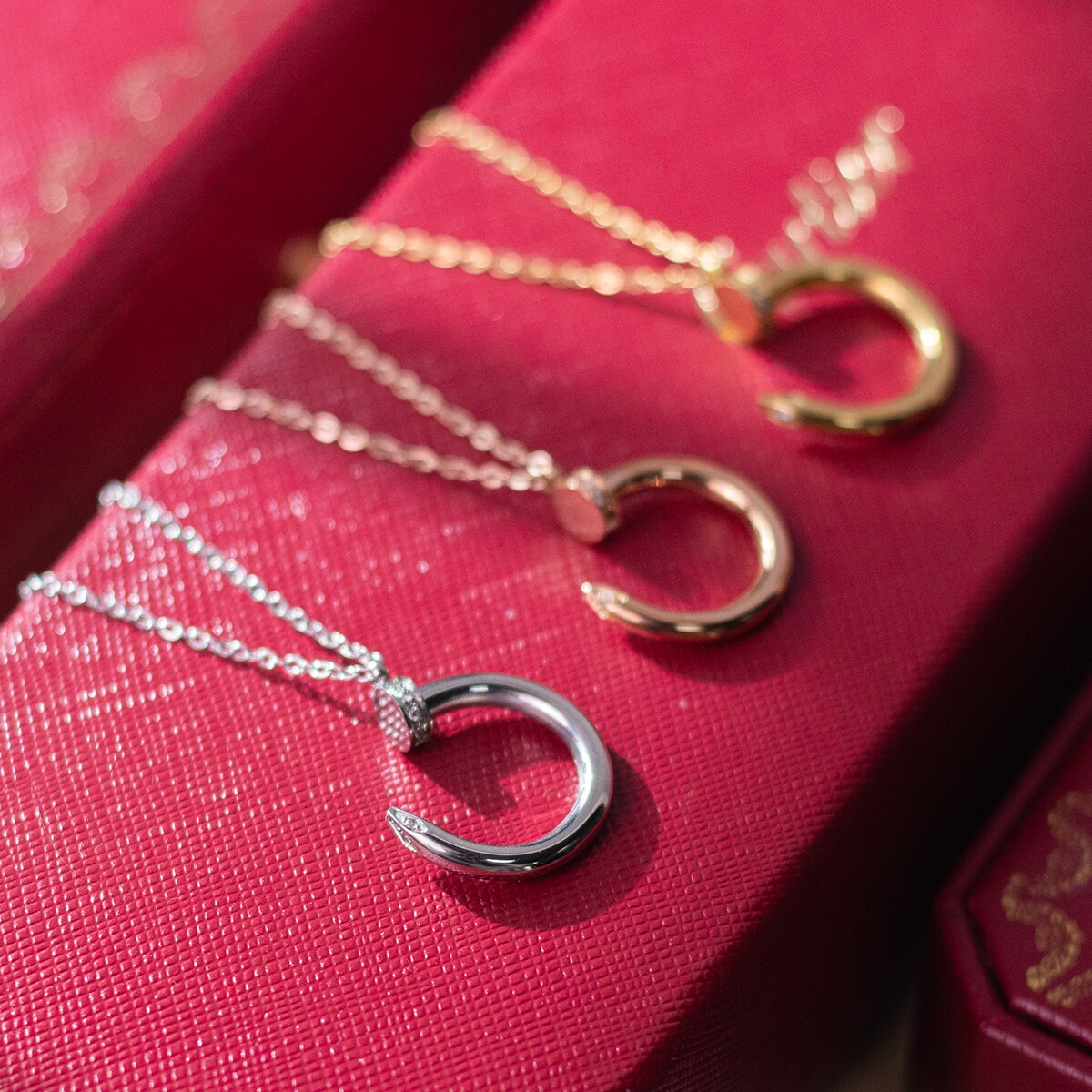 Close view of three nail motif pendants on their chains