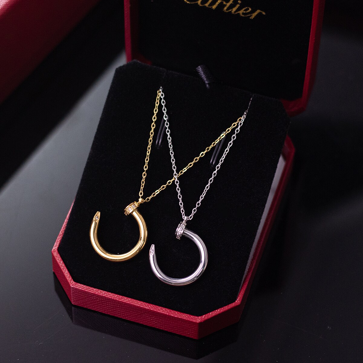 Two nail motif pendant necklaces shown side by side